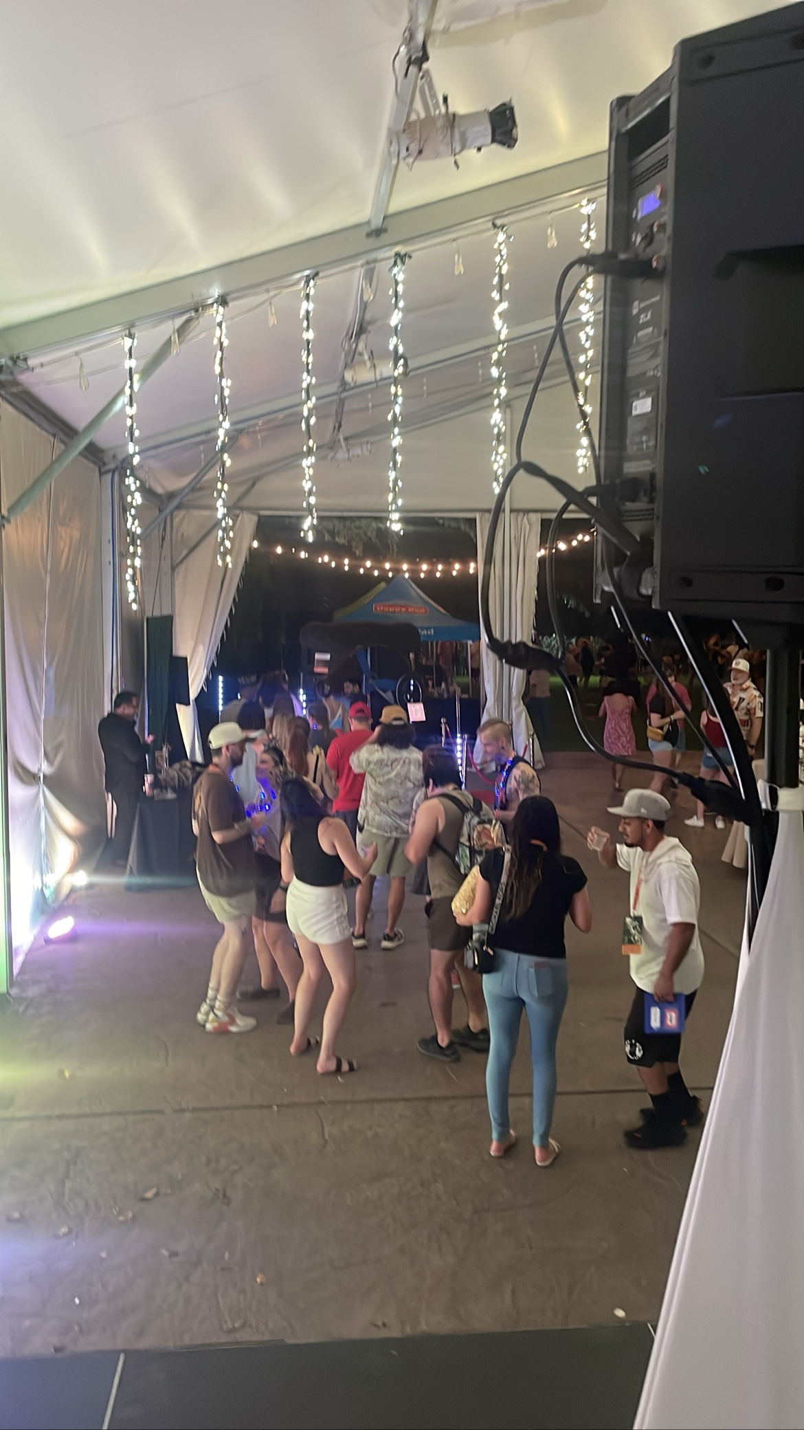 Outdoor tent party with string lights and a packed crowd