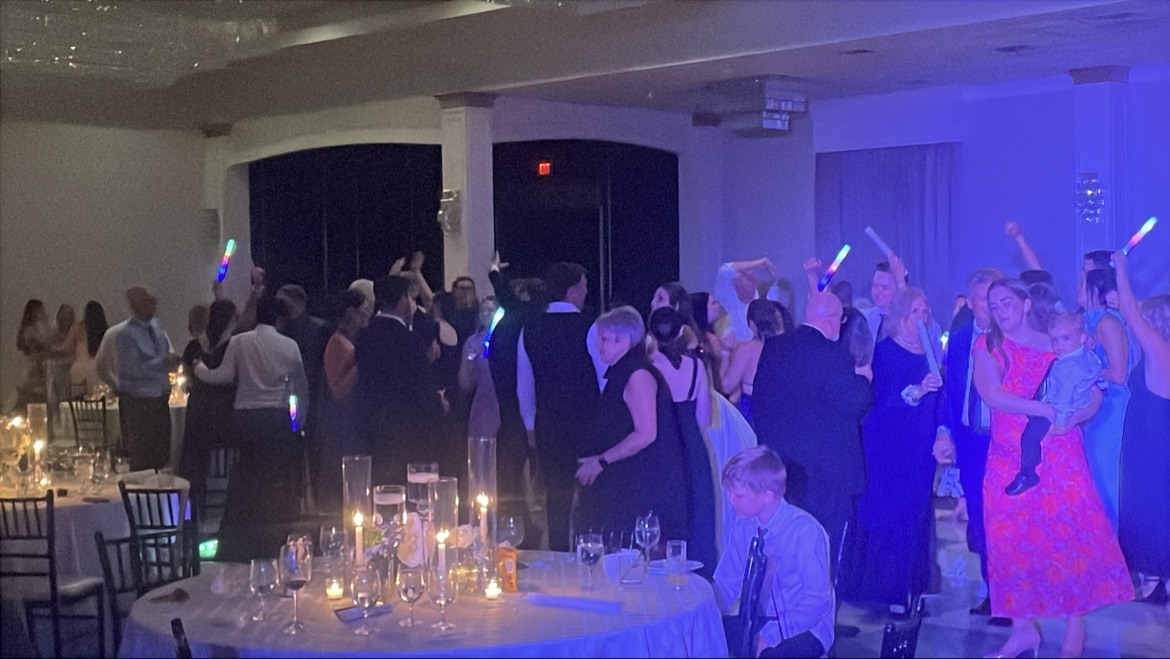 Wedding reception under purple lights with glow sticks and candlelit tables