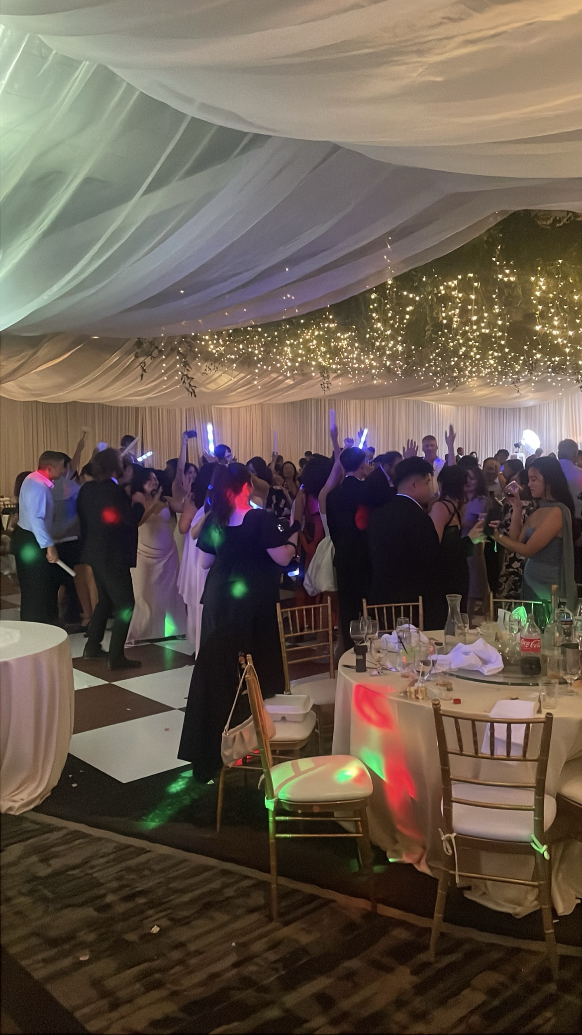 Wedding guests dancing under a draped ceiling with glow sticks