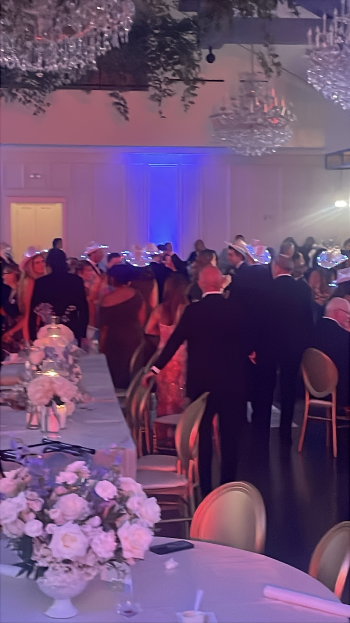 Wedding ballroom with chandeliers, guests dancing under blue uplighting