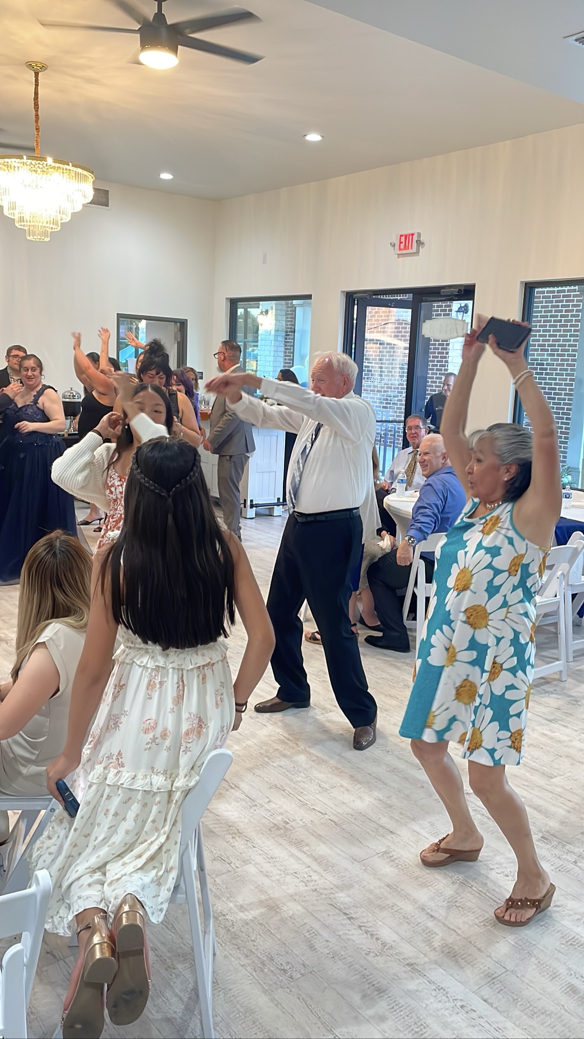 Guest dancing with arms up while a woman films on her phone