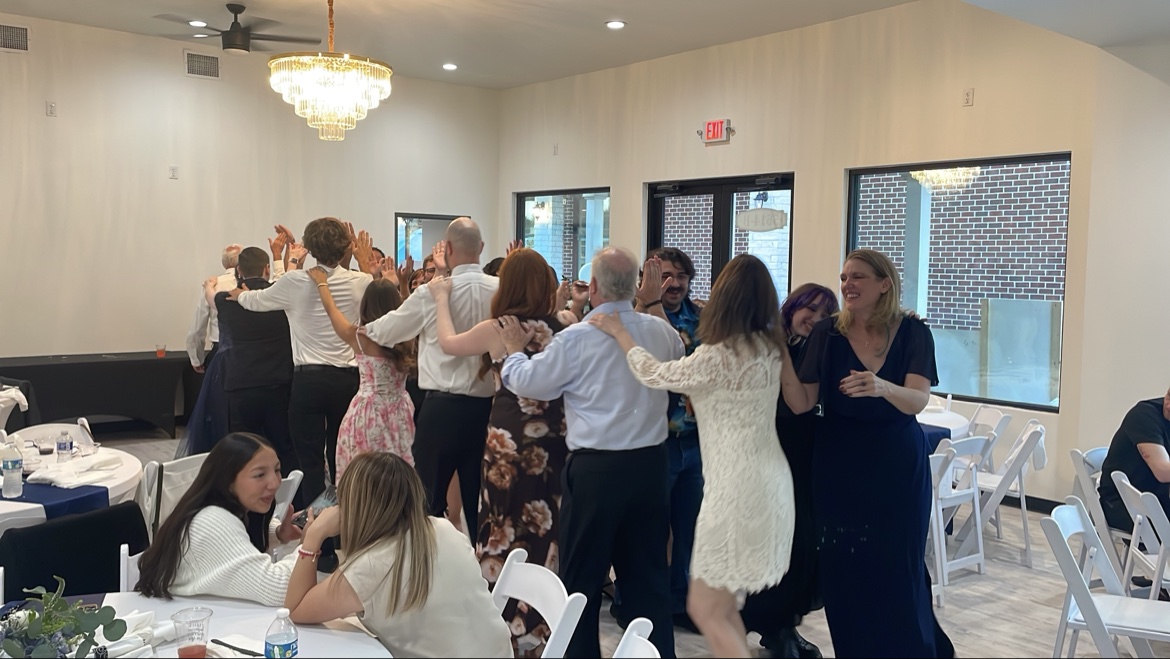 Guests line dancing with hands on shoulders