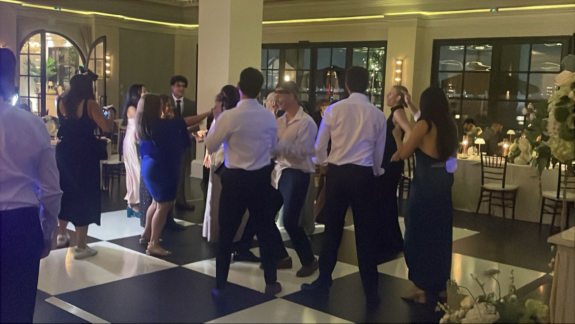 Guests dancing on a checkered floor in front of night windows