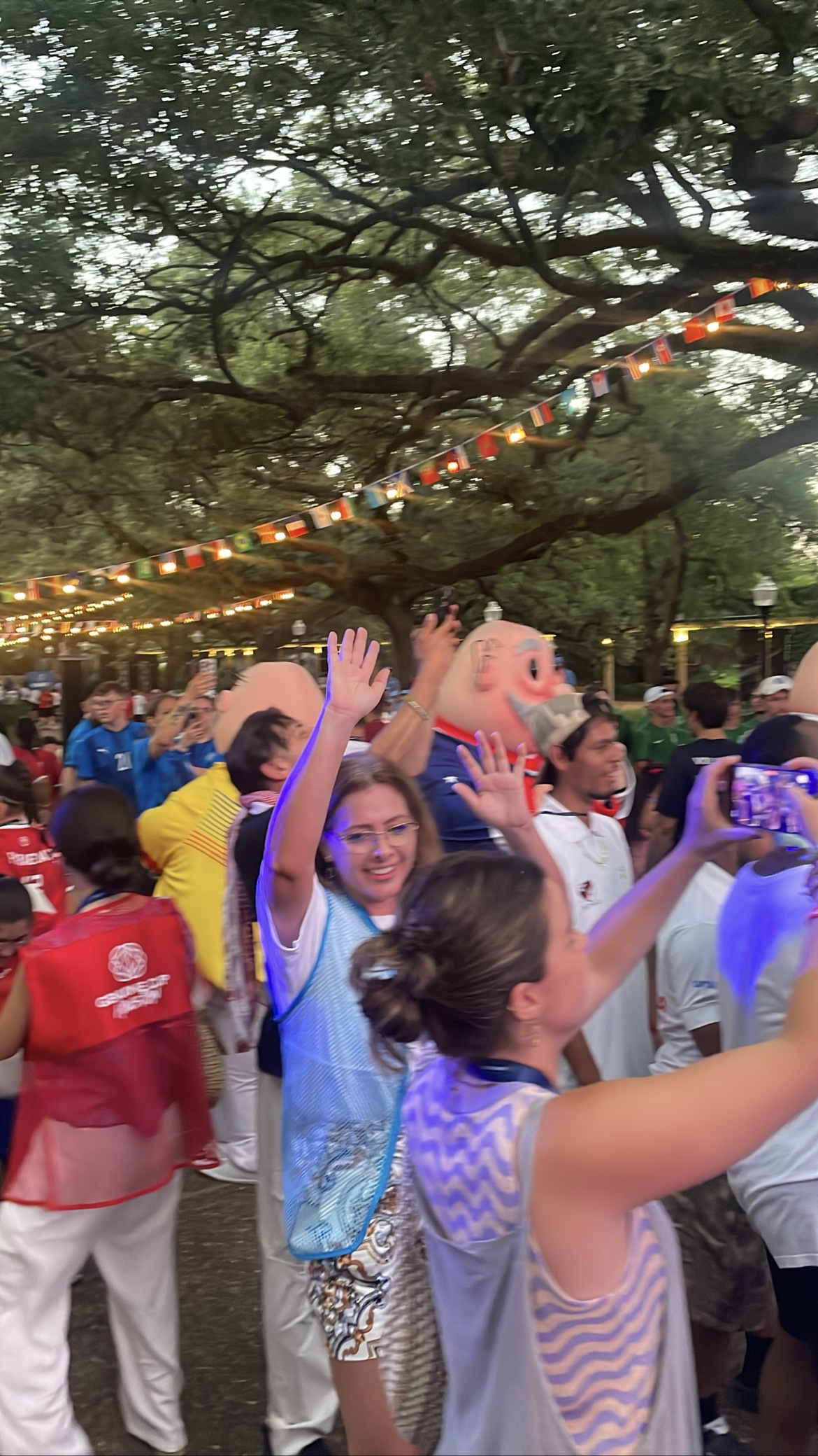 Outdoor festival crowd waving under string lights with mascot characters