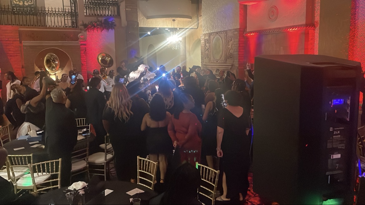 Wedding crowd around a brass band with tubas under red uplighting