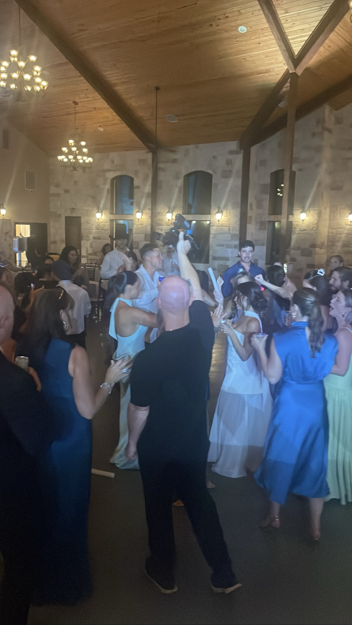 Wedding guests dancing with glow sticks in a stone hall